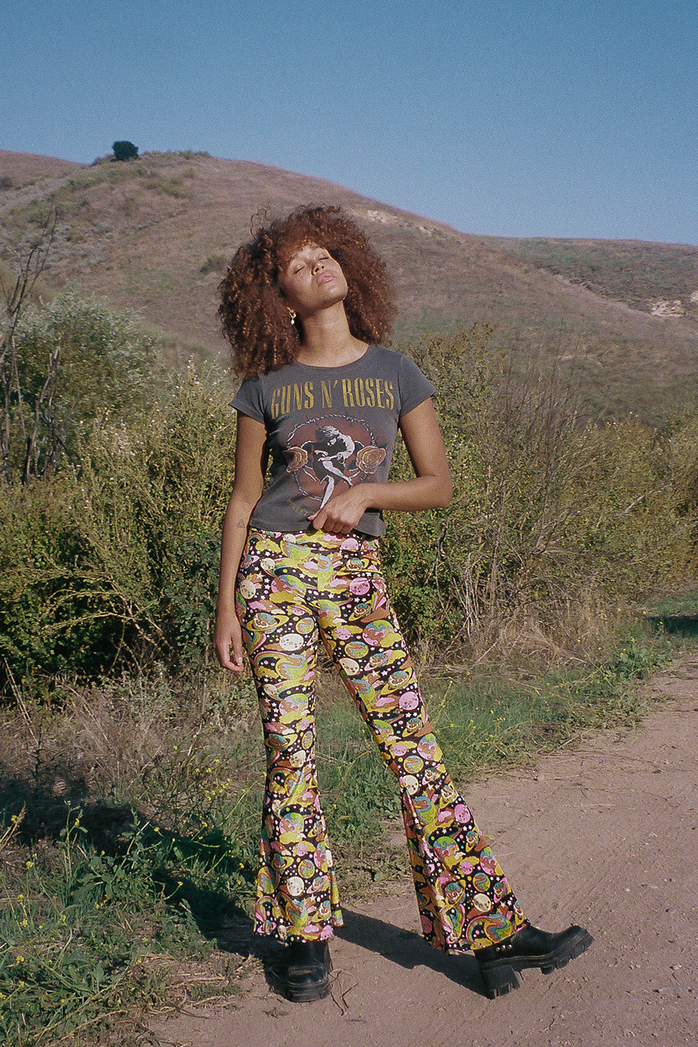 Trippy, velvet bell bottom style pants with galactic design featuring green, pink, brown and black.