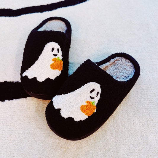 Halloween themed pair of black fuzzy slippers with white ghost and orange pumpkin design