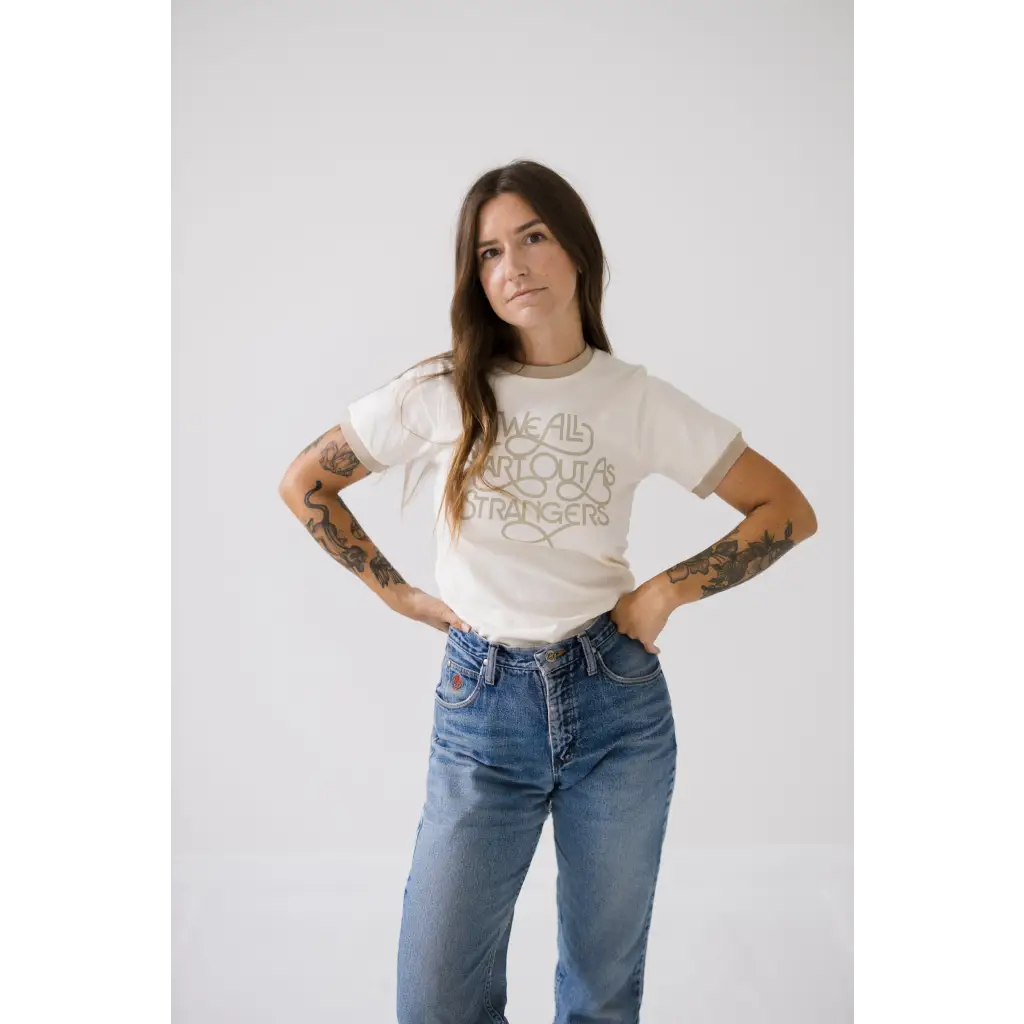 Ringer tee with beige trim with “we all start out as strangers in fancy” script.