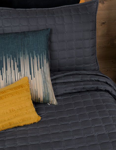 Bed featuring black Centauro Quilt Set with boxed embroidery throughout.