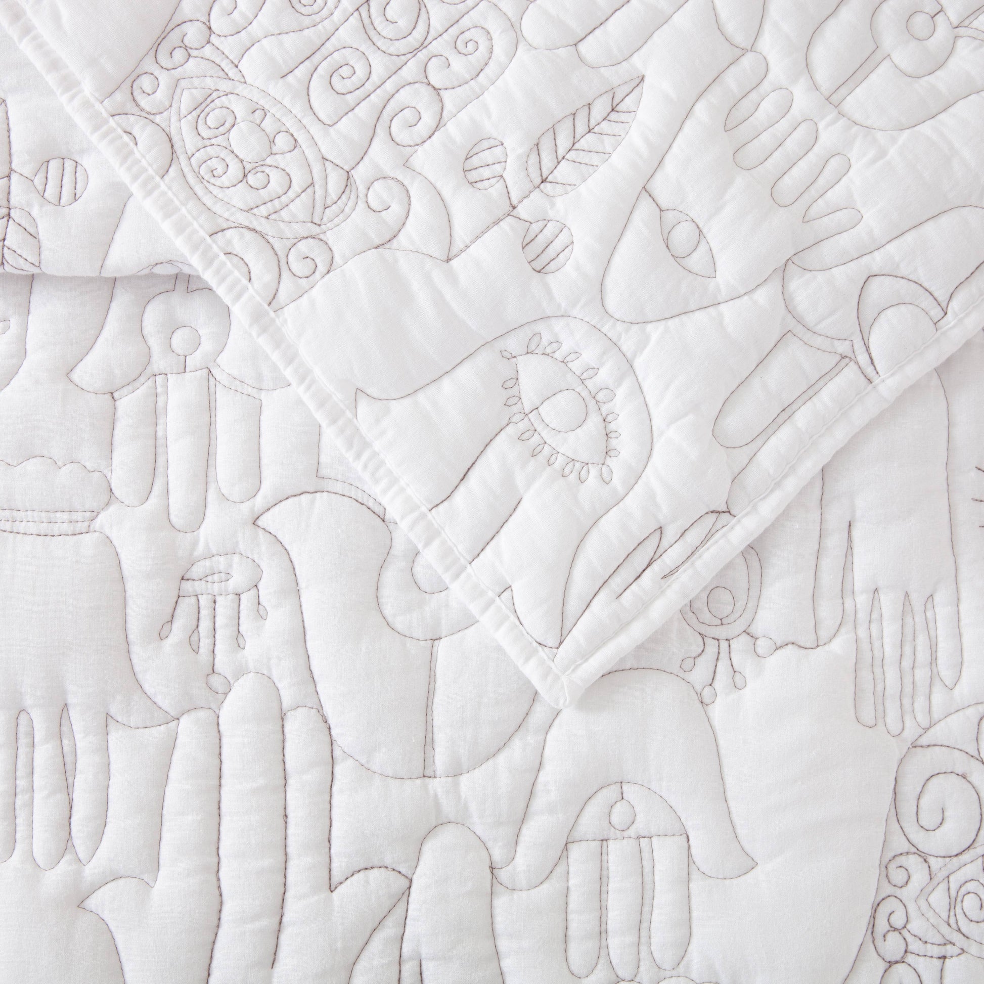 Close up of stunning Hamsa stitching over white quilt