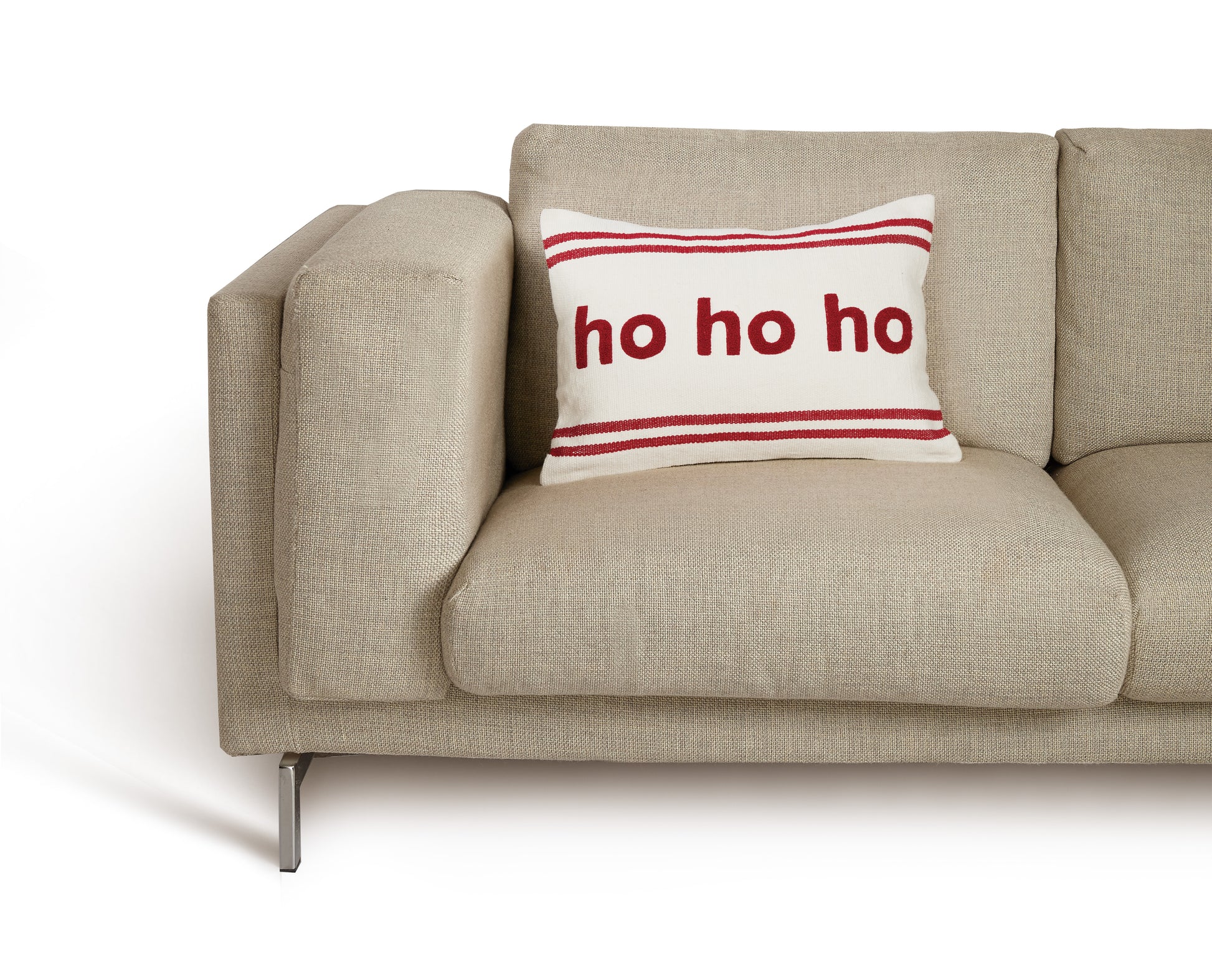 Tan mid-century modern couch displaying white pillow with red stripes and “ho ho ho” in the center 