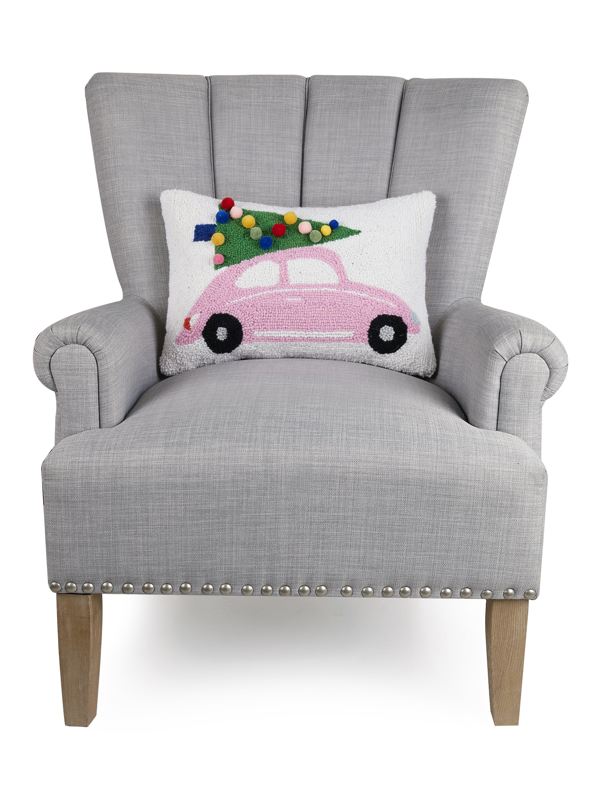 Gray chair displaying retro pink VW beetle on white pillow hauling Christmas tree with 3D pom poms