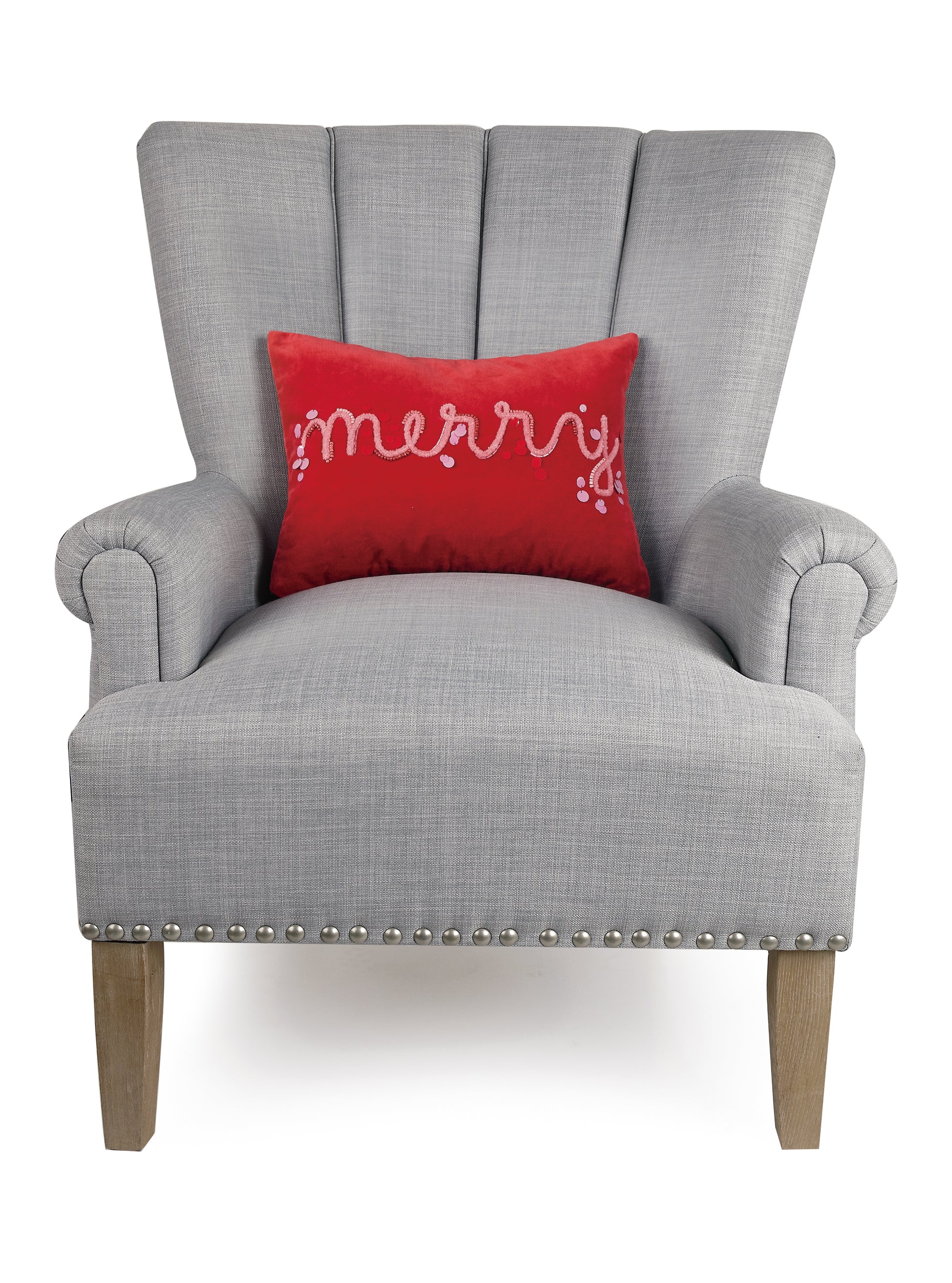 Bright red “merry” holiday pillow with scattered sequins styled with gray sitting chair