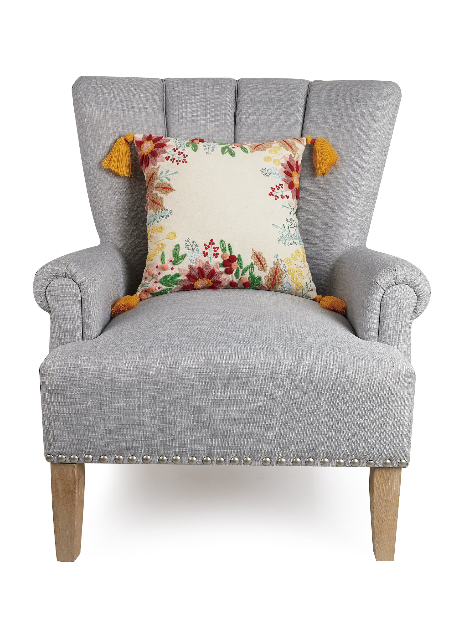 Gray chair showcasing orange tassel pillow with multicolored fall floral embroidered and hooked design