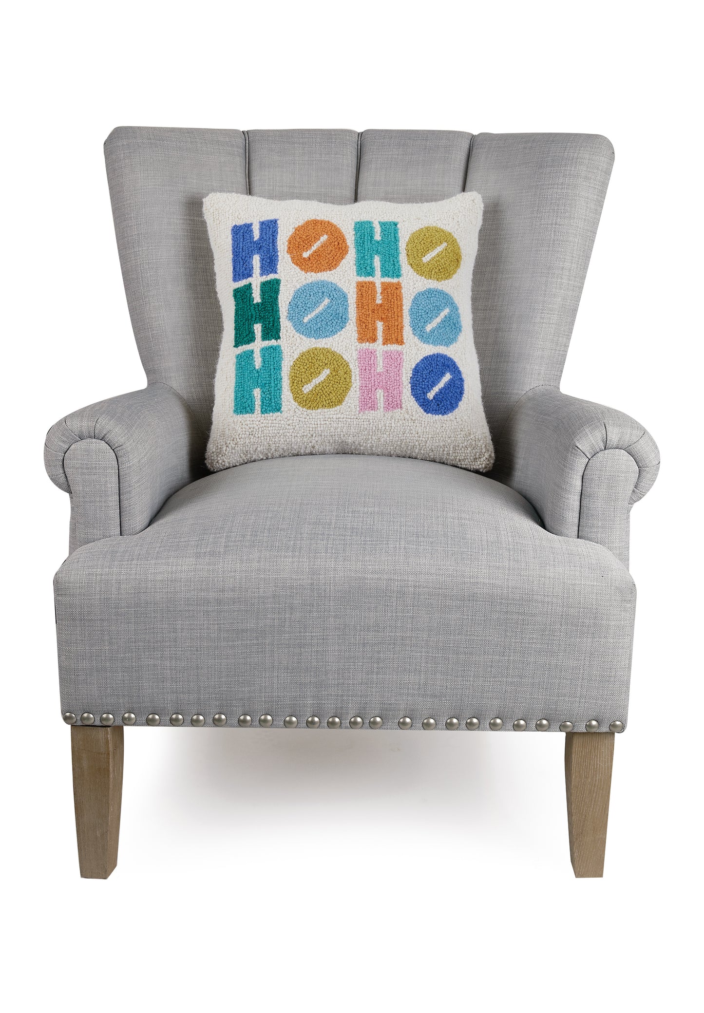 White wool hooked pillow with blue, orange, green and pink Ho Ho displayed in gray sitting chair