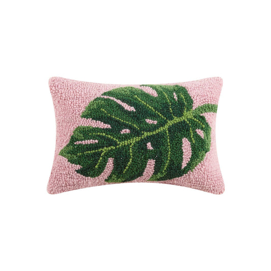 Pink throw pillow with green palm leaf displayed across the center