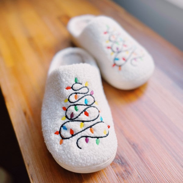 White slippers with a string light Christmas tree design on a fuzzy fabric