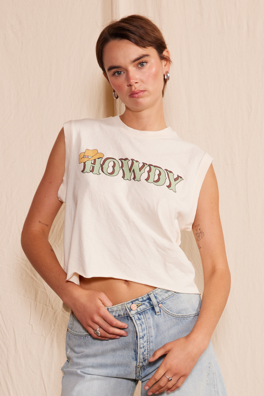 Ecru/natural colored organic muscle tank top for juniors or women with green “howdy” text in western print and cowboy graphic.
