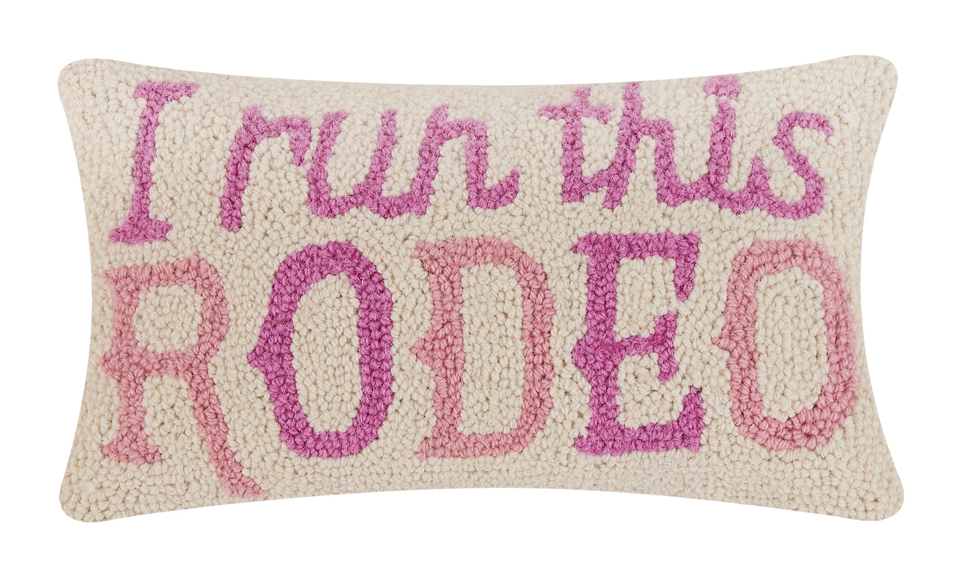 Soft wool hooked pillow with cream background and purple and pink text that reads, “I run this RODEO.”