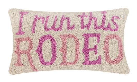 Soft wool hooked pillow with cream background and purple and pink text that reads, “I run this RODEO.”