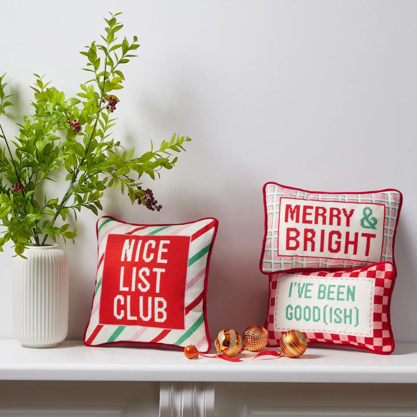 Shelf decorated with various red, white and green novelty holiday pillows including the “I’ve been good(ish) pillow.