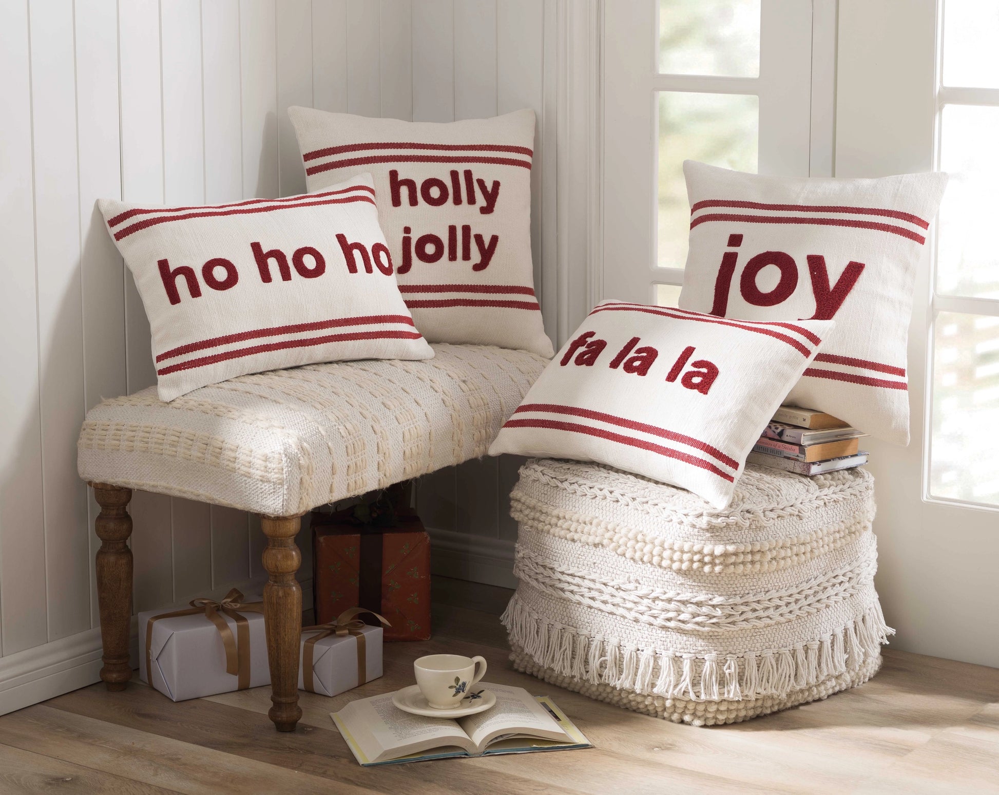 Home corner with various red and white holiday pillows on cream colored stools. 