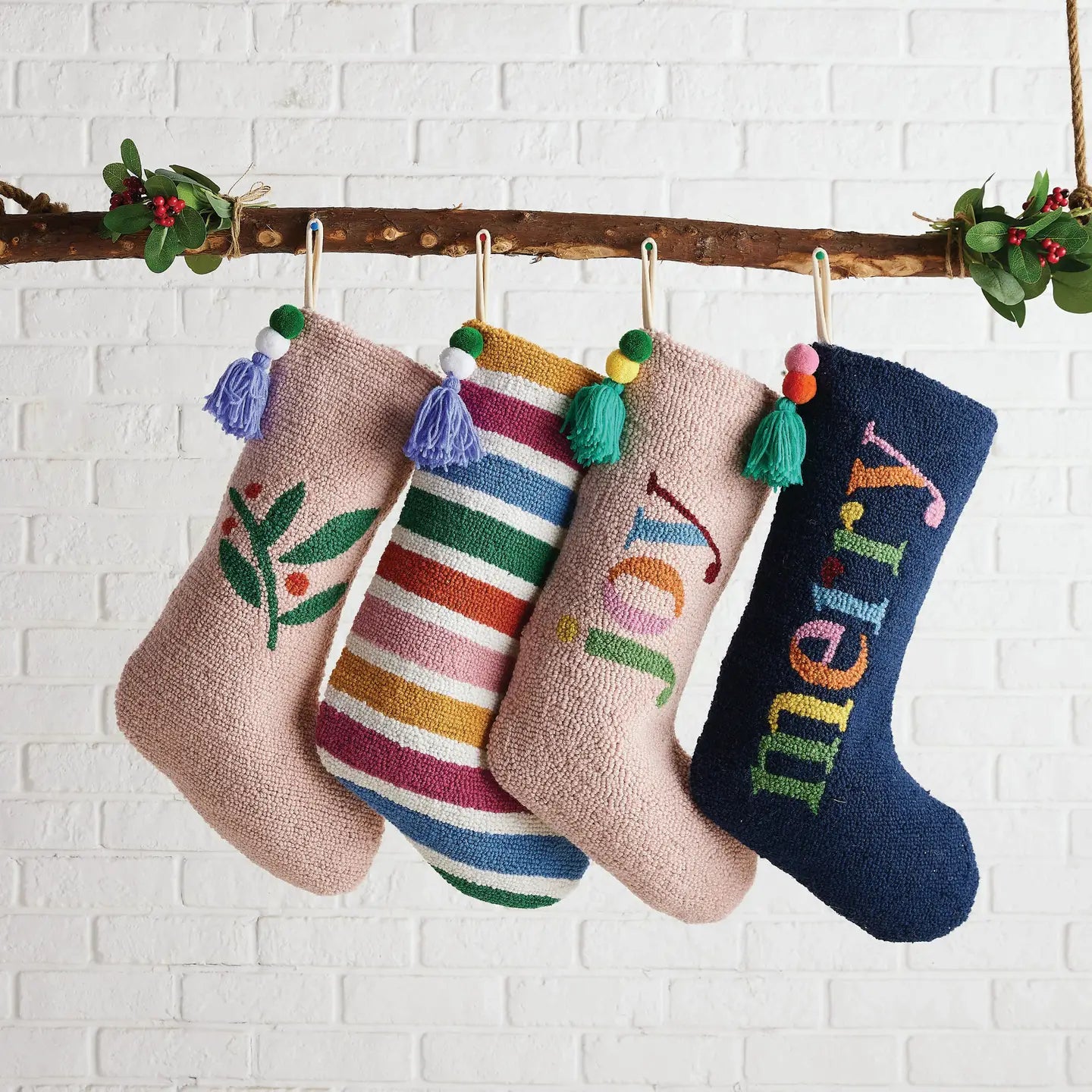 Colorful holiday display of decorative stockings hanging from a branch with mistletoe, rainbow and novelty designs.