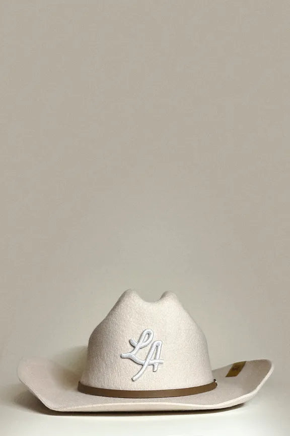 Cool cream wool cowboy hat, for unisex wear, with “LA” embroidered in white cursive letters with faux leather brown trim.
