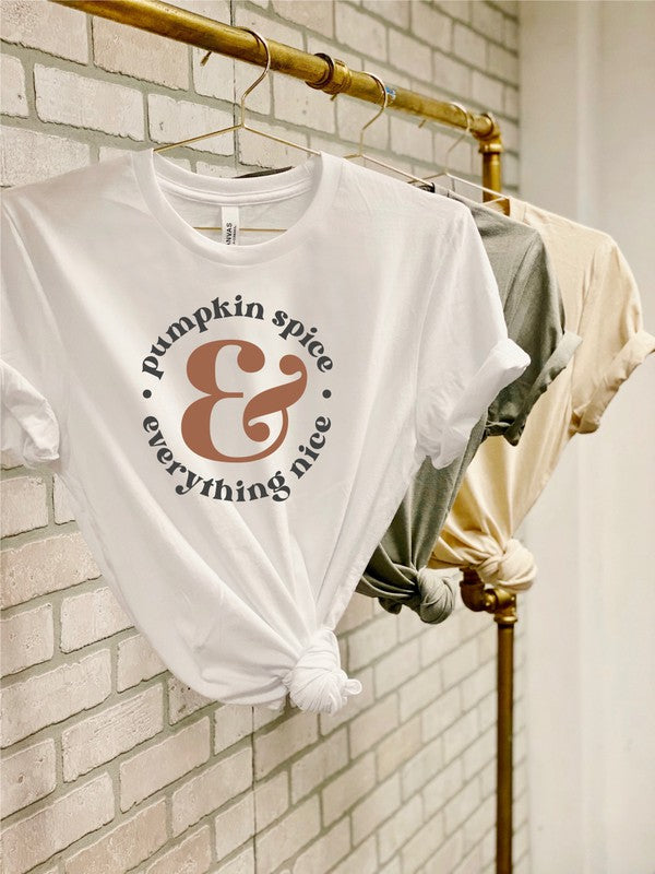 White t-shirt with 'pumpkin spice & everything nice' text on a rack against a brick wall.