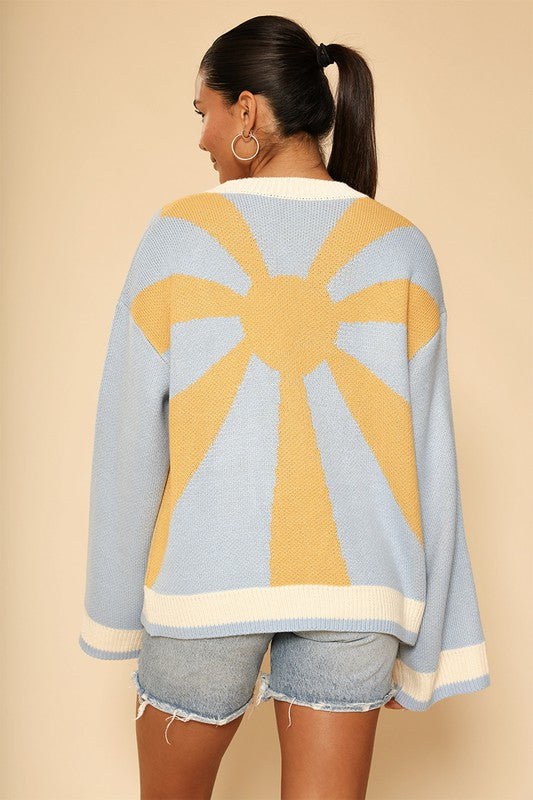 Light blue knit cardigan with golden boho sunburst design on back and white stripe trim along collar and bottom