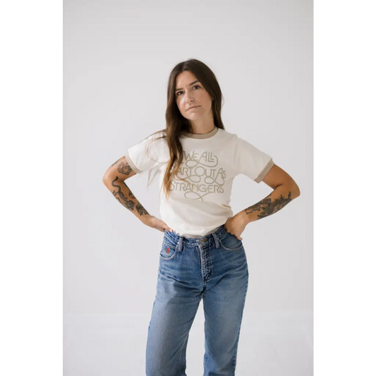 Ringer tee with beige trim with “we all start out as strangers in fancy” script.