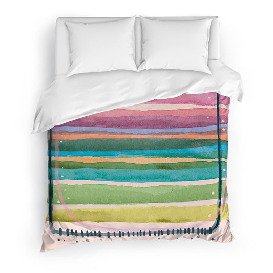 Clean bed with printed duvet cover adorned with watercolor brushstrokes in pastel tones.