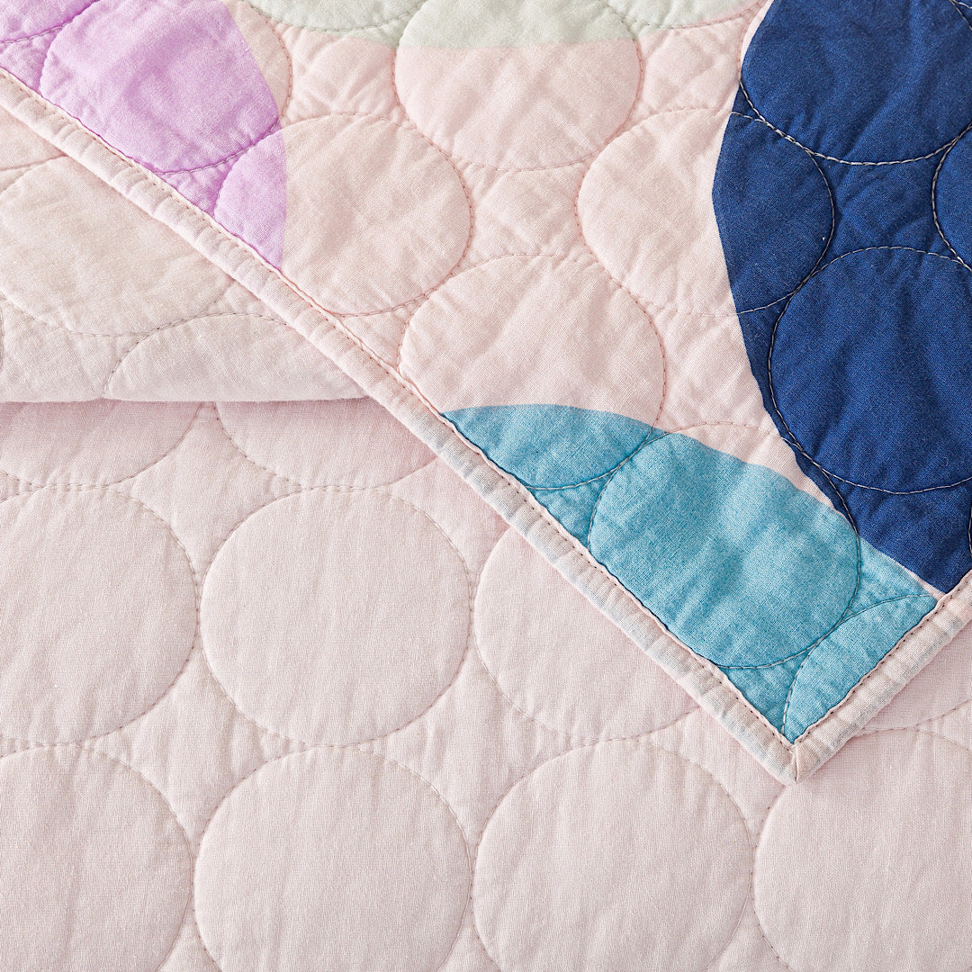 Close up of reversible quilt with color blocked circle design.