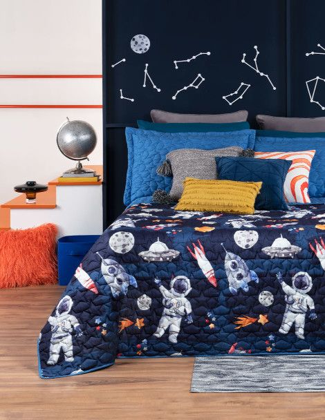 Kid’s bedroom with galactic theme featuring blue reversible 3D quilt with astronauts and star design.