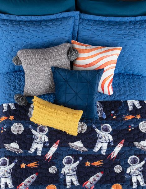 Boy’s bed highlighting navy blue Astro quilt with bright blue star stitching on reverse.