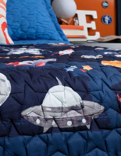 Close up 3D quality of blue quilt featuring spaceships, stars and rockets.