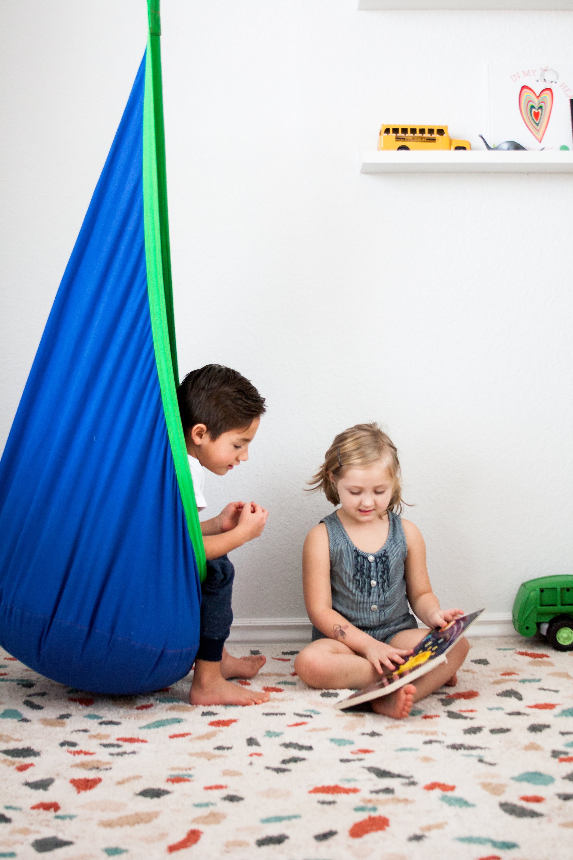 Kids engaging while using indoor therapy swing in blue with green trim.