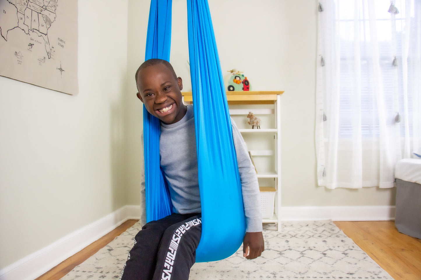 Smiling boy seated in durable indoor therapy swing.