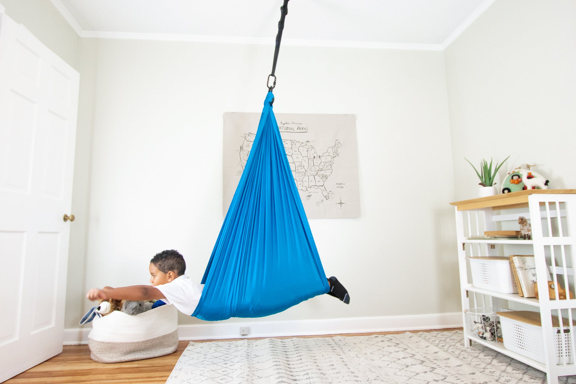 Boy swinging proudly from Harkla compression swing in playroom.