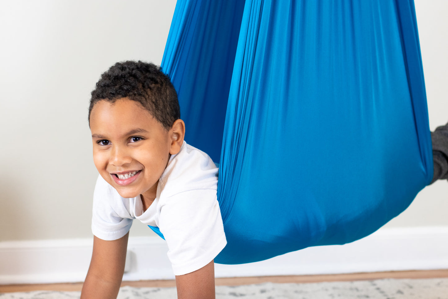 Boy happily hanging in stretchy compression therapy swing.