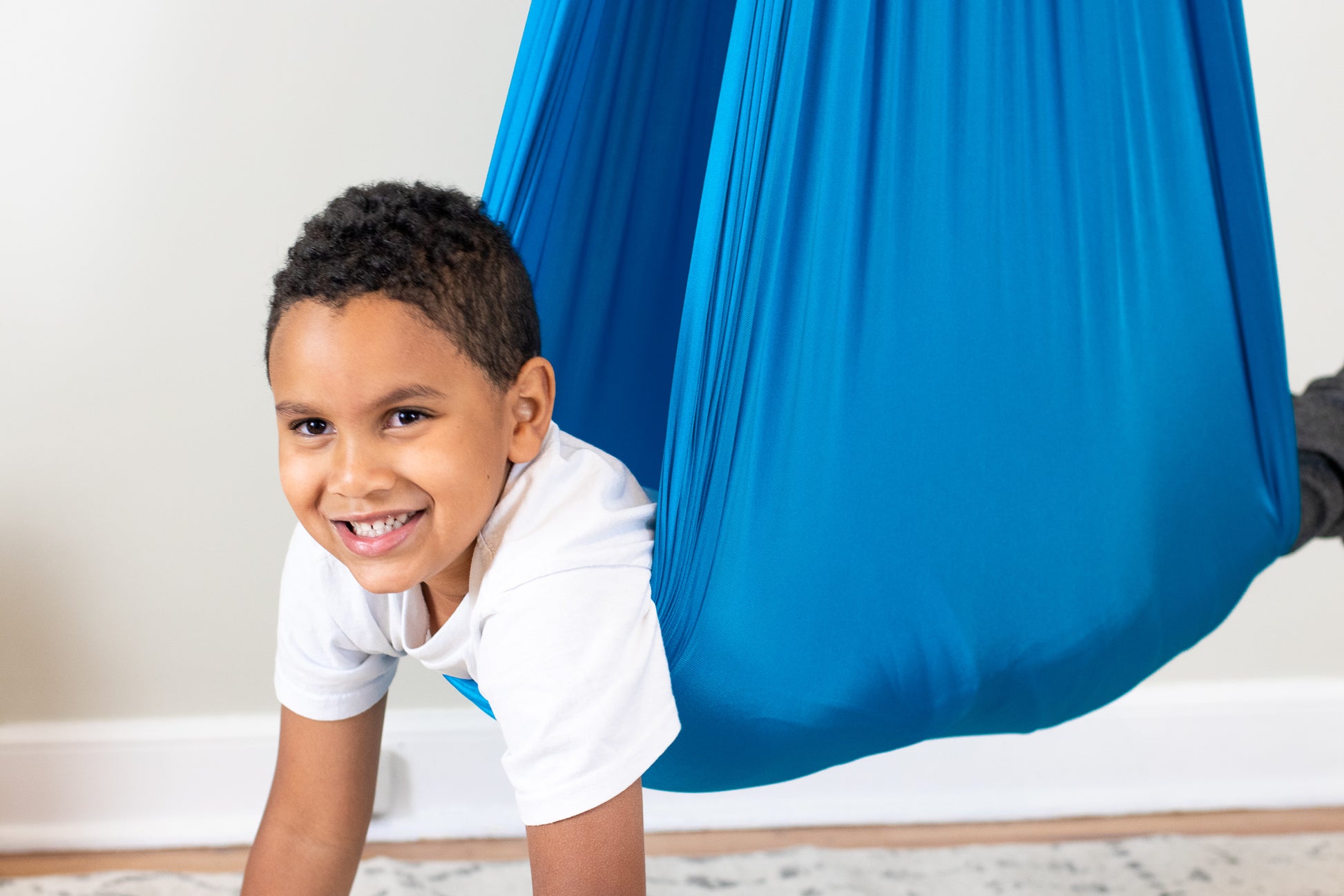 Boy happily hanging in stretchy compression therapy swing.