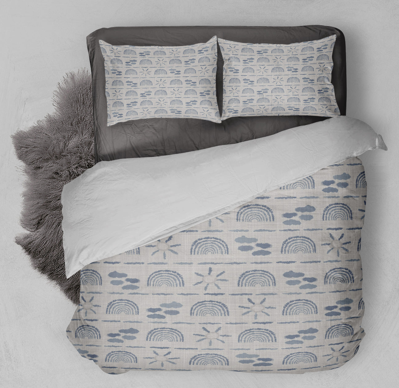 Close up of bed featuring playful duvet set with neutral rainbow sky theme and complementary shag rug.