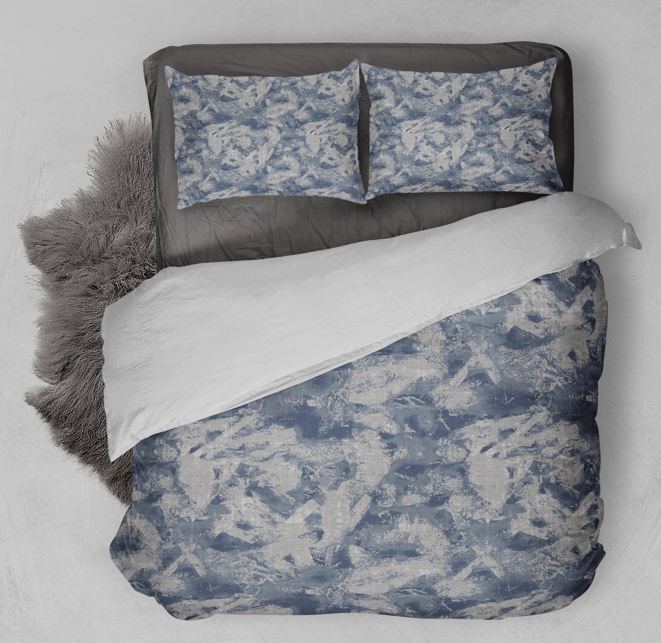 Inviting bed displaying duvet covet set with abstract blue and gray marble design and shag rug.