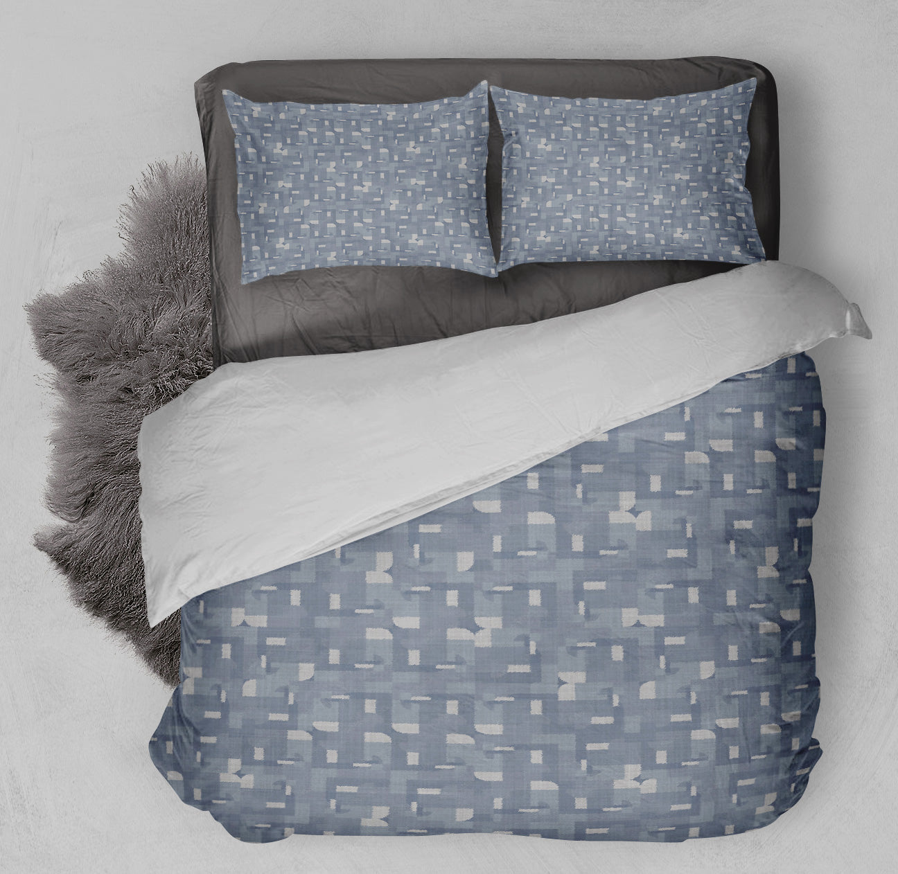 Clean bed featuring printed blue and white Comforter Set with crisp Kaleidoscope design and coordinating gray shag rug.