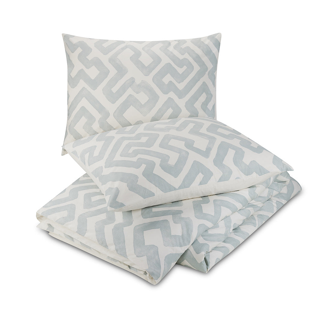 Two pillows atop matching gray and ivory patterned duvet cover by Lemieux Et Cie