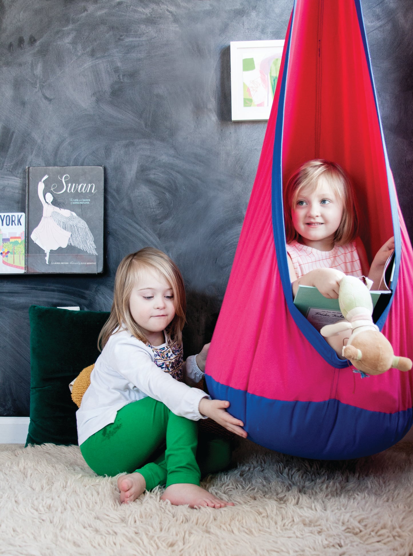 Two young girls enjoying playtime featuring indoor Calming Cove Sensory Swing.