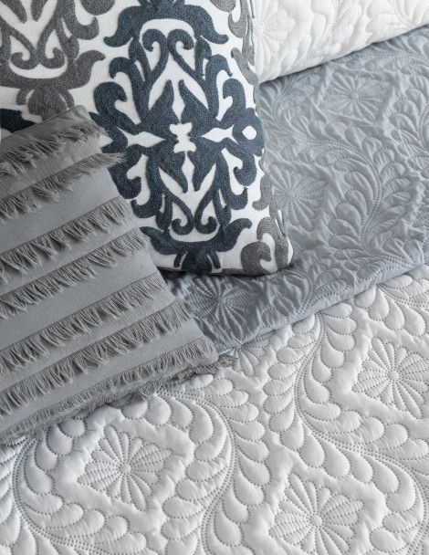 Bedding featuring luxuriously embroidered gray and white quilt with reversible 3D effect.