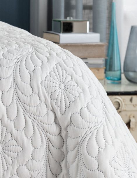 Corner view of white Victoria 3D Quilt with embroidered diamond floral design.