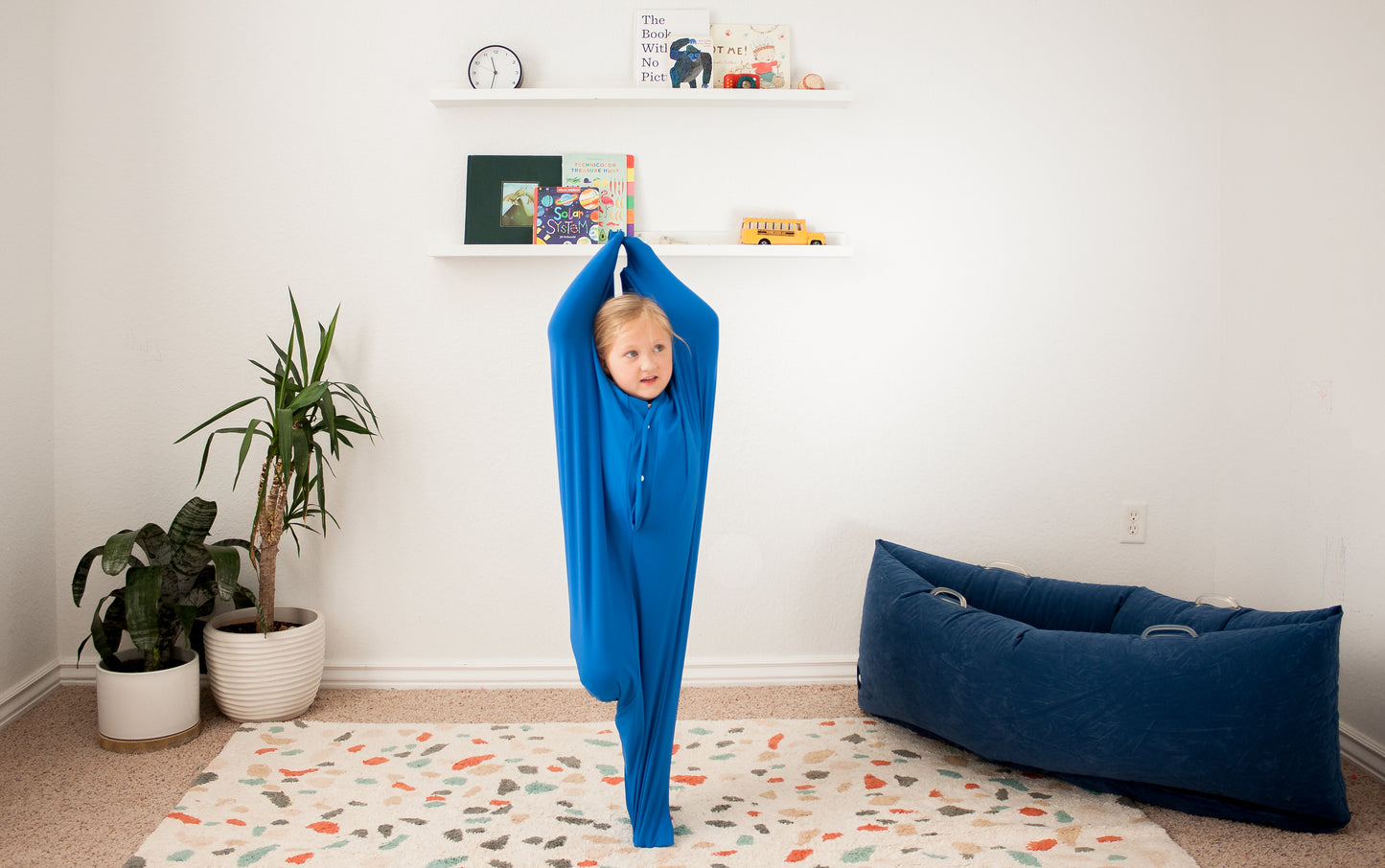 Focused young girl in sensory body sock while practicing Vrikshasana Tree Pose.