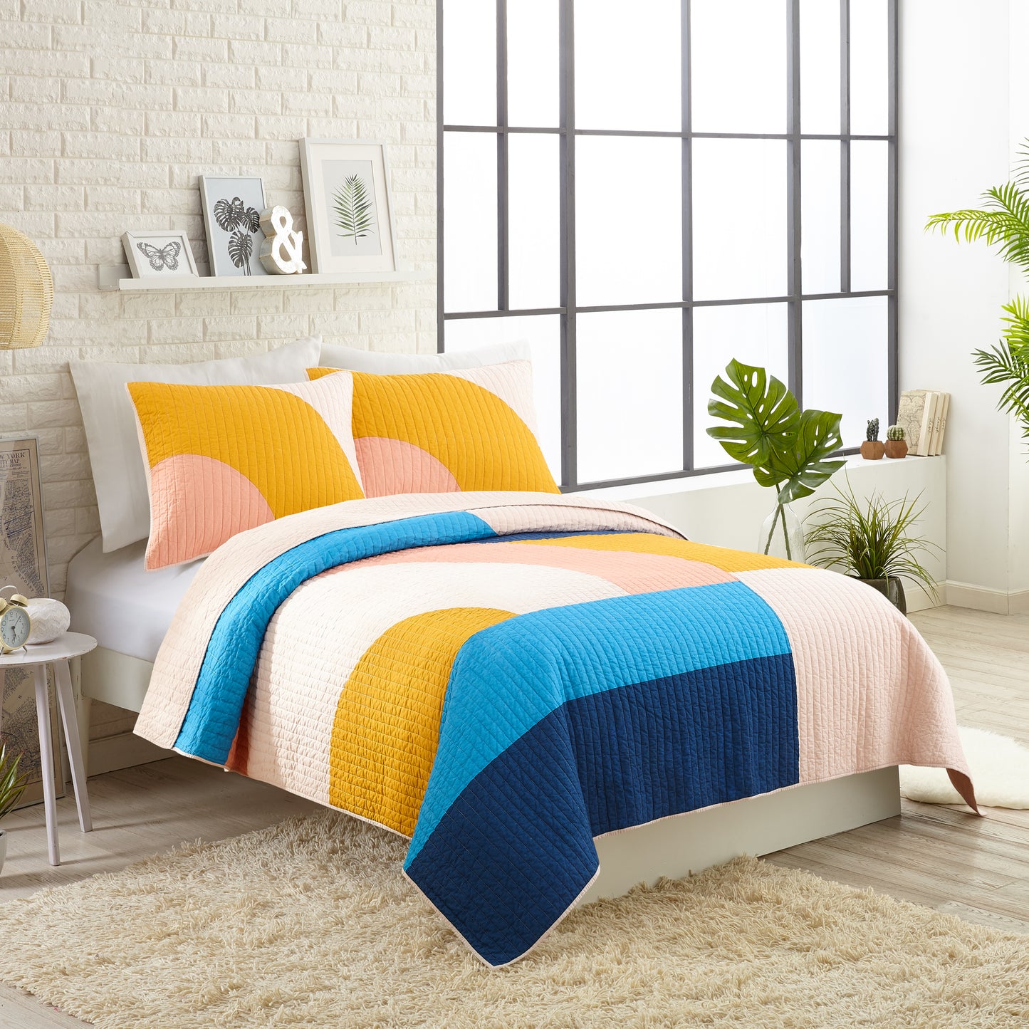 Modern style bedroom featuring modern quilt set with colorful, connecting shapes in yellow, blue and pink.