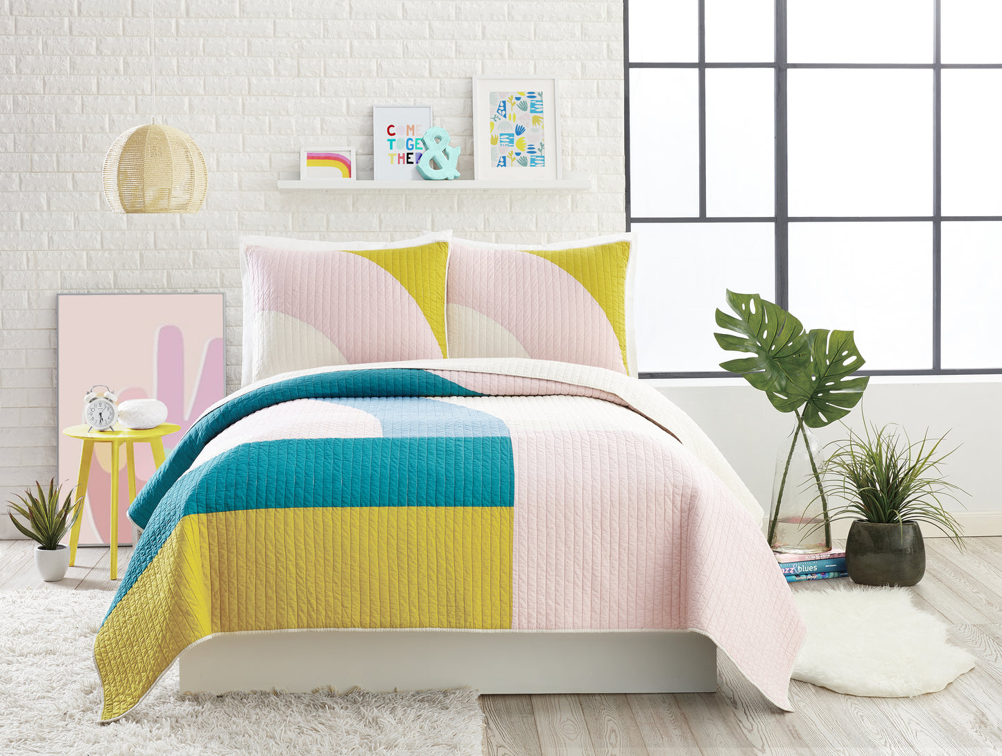 Modern style bedroom featuring modern quilt set with colorful, connecting shapes in green, blue and pink.