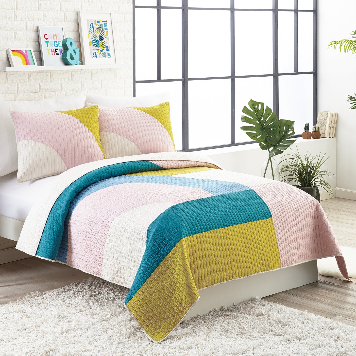 Modern style bedroom featuring modern quilt set with colorful, connecting shapes in green, blue and pink.