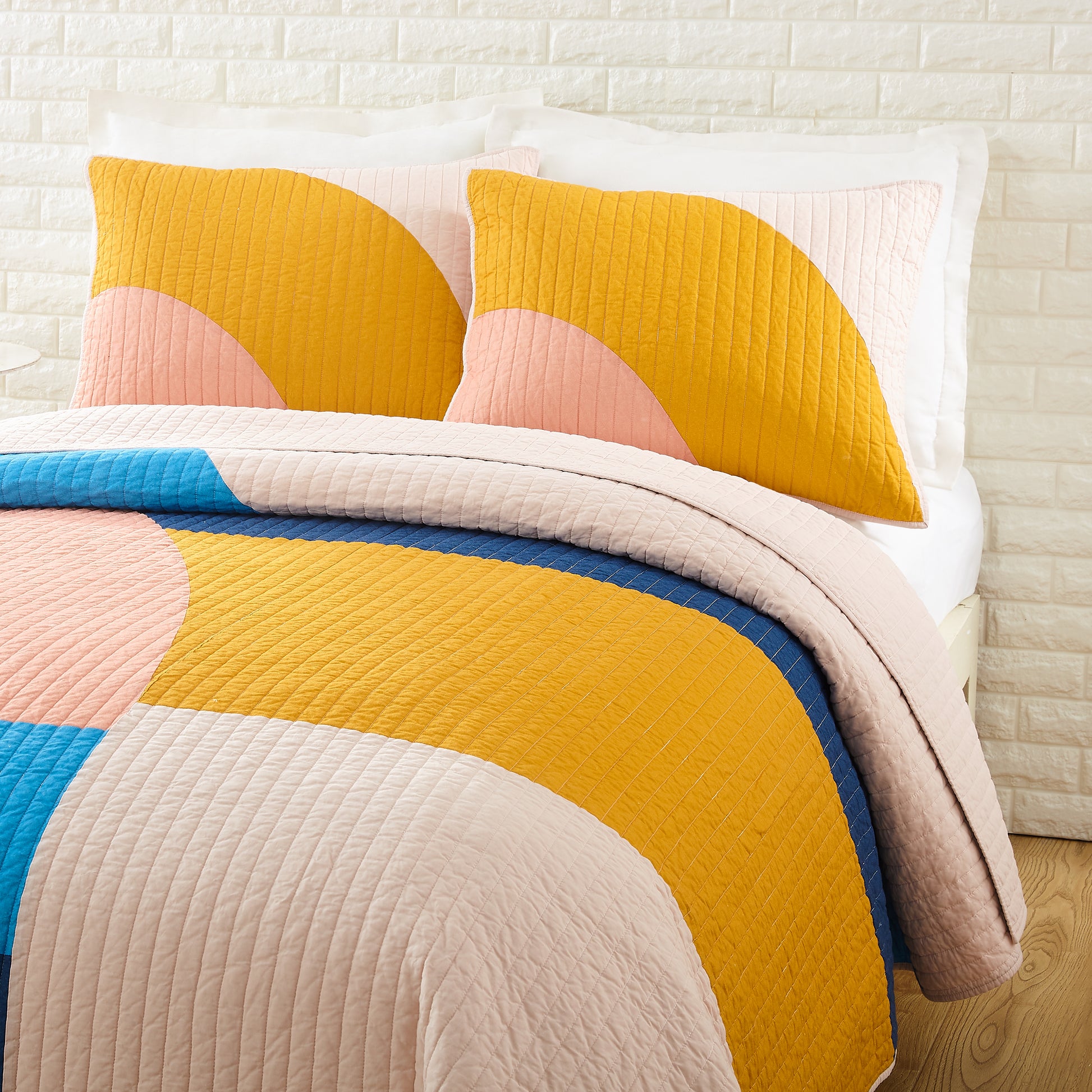 Bedding decor with colorful, connecting shapes in yellow, blue and pink.