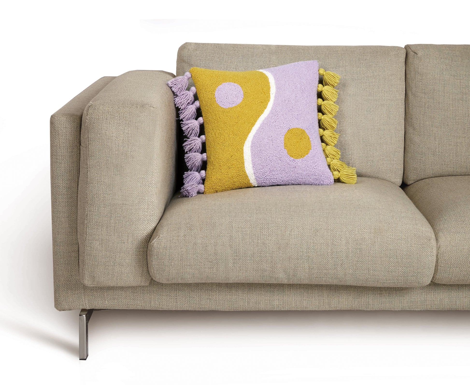 Ampersand purple and yellow yin yang tassels pillow against beige Mid-Century sofa.