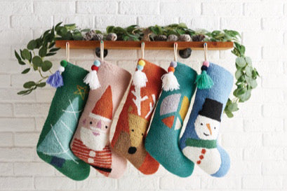 An assortment of Christmas stockings hanging from decorated mantle.