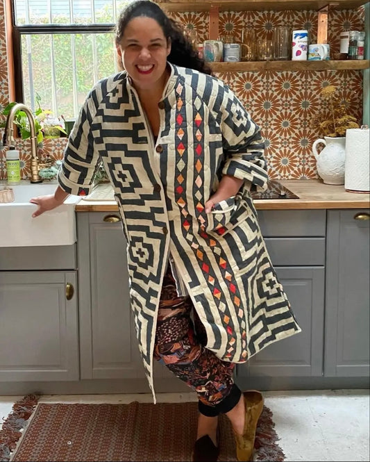 Justina Blakeney, smiling in a kitchen, wearing the Hypnotic Robe in Black and White.